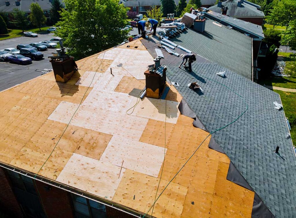 Technician examining a modern roof with an infrared camera beside reflective shingles and solar panels.